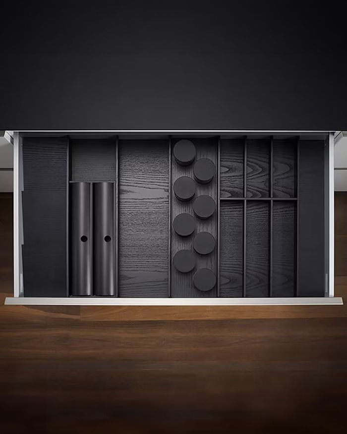 The photograph captures a perfectly organized kitchen drawer from the MosaiQ series by Kessebohmer, offered by Mebel Arts. The dark colored surface exudes a sense of luxury and contemporary aesthetic, while the variety of partitions and storage compartments provide practical solutions for organizing and storing cooking utensils and tools. The image reinforces Mebel Arts' image as synonymous with adaptability and high aesthetic in the kitchen space.
