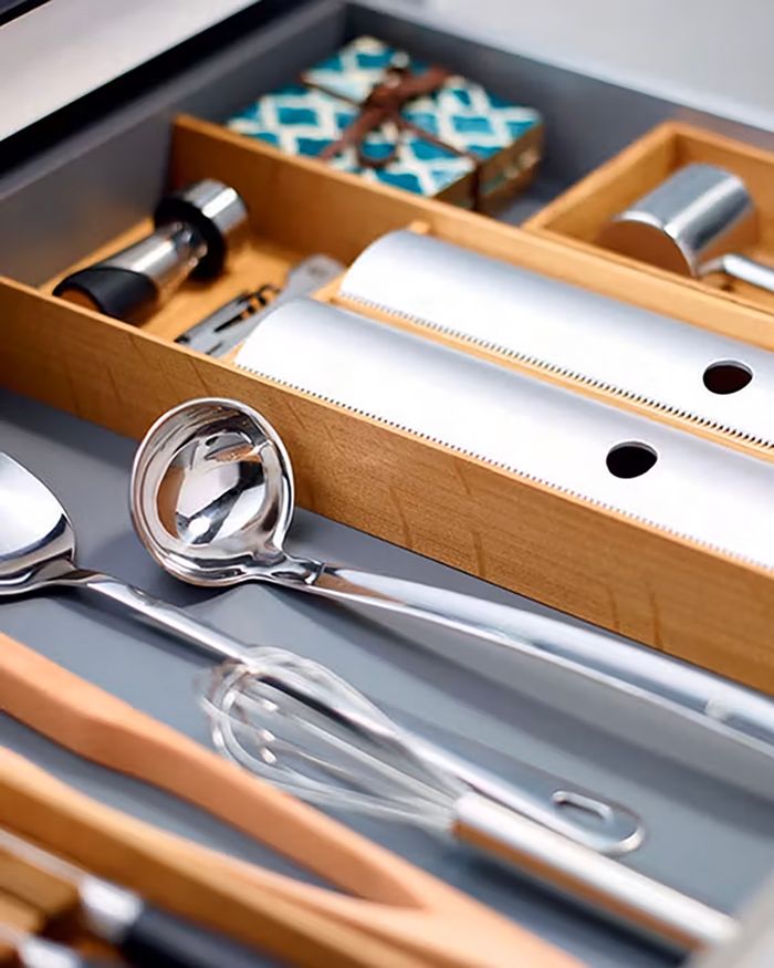 This image highlights an elegantly organized kitchen drawer equipped with cutlery holders from the MosaiQ series by Kessebohmer, as used in Mebel Arts furniture. The drawer provides an easy and functional way to arrange utensils, while the wooden partitions add a sense of natural beauty. The meticulous arrangement of cutlery and cooking tools emphasizes adaptability and the quality aesthetics of modern kitchens.