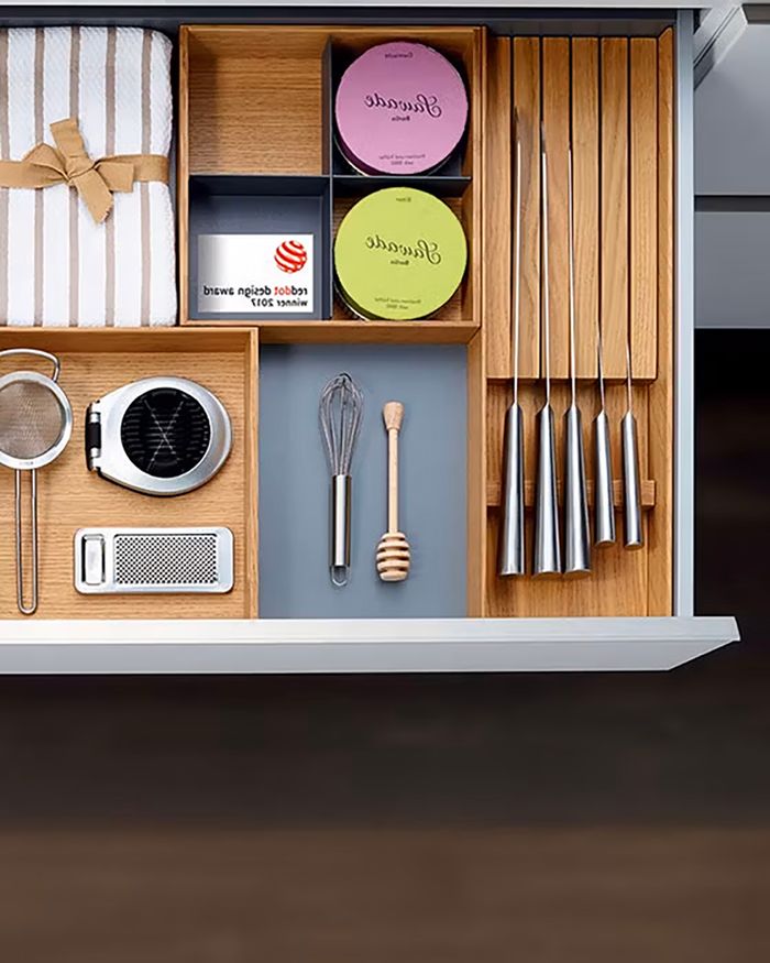 The image shows a MosaiQ knife holder made of natural wood with tasteful German design, filled with cooking tools, maintaining an elegant and functional space in the kitchen. The tools and knives are arranged in a way that favors easy access and ergonomic use, while the holder integrates harmoniously with the modern aesthetic of the kitchen.