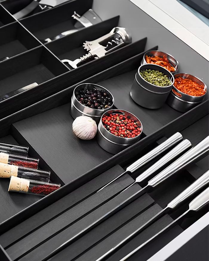 The image presents an elegant black Kessebohmer MosaiQ knife holder, which combines elegance with functionality in a modern kitchen space. The knives and spice jars are neatly arranged, providing easy access and an organized workspace.