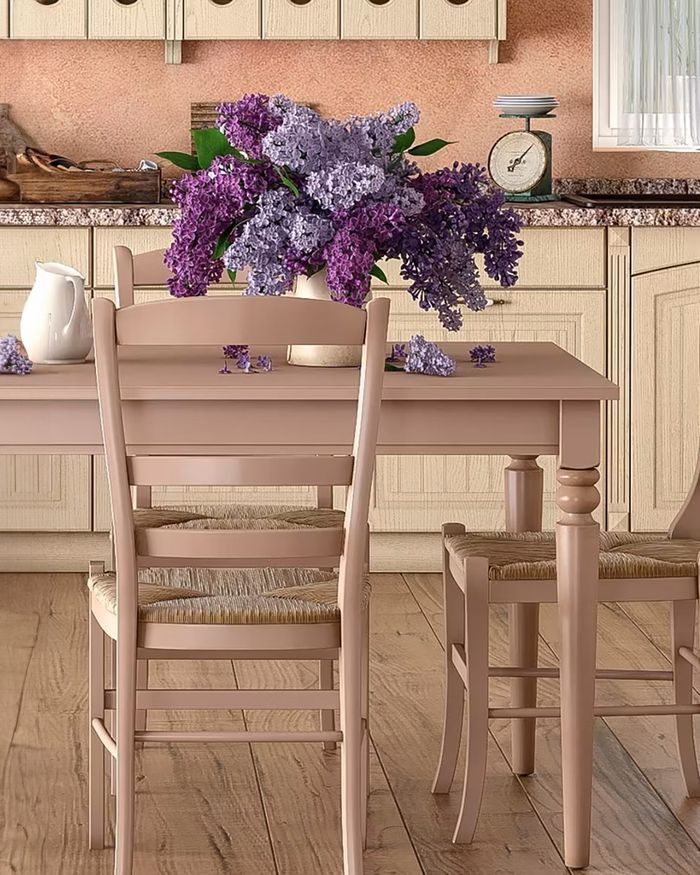 The image depicts a warm and inviting breakfast nook in a kitchen from the INTER series by Mebel Arts. The dining set with wooden furniture and wicker chairs offers a sense of classic elegance and comfort, while the large bouquet of flowers adds a touch of color and natural beauty to the space. Attention to detail and the use of natural materials showcase the quality and aesthetics that Mebel Arts provides.