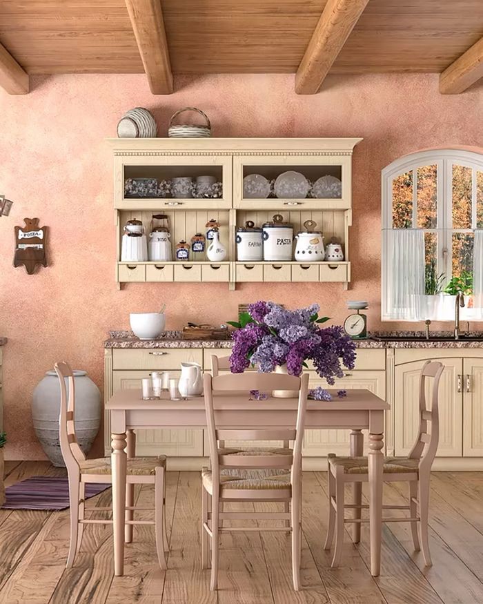 The image depicts a kitchen from the INTER series by Mebel Arts with a rustic aesthetic, creating a warm family space. The wooden beams and the natural light flowing in from the window enhance the warmth and classic elegance. The space combines functional storage with an attractive design, making the kitchen ideal for social and family gatherings.
