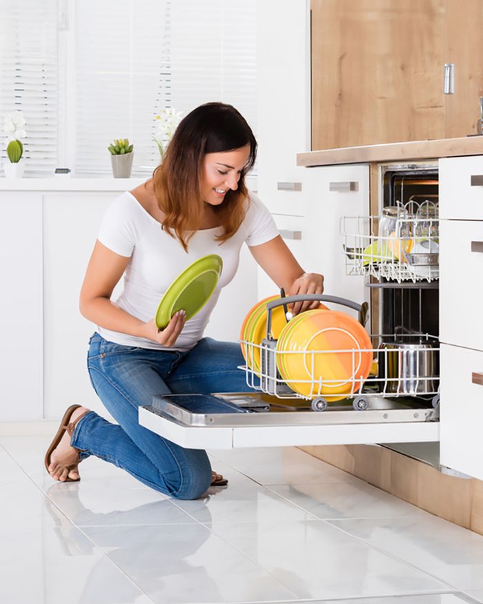 La photographie présente une femme souriante chargeant un lave-vaisselle avec des assiettes colorées dans une cuisine lumineuse et bien organisée. Cette image met en avant la facilité d'utilisation et l'efficacité du lave-vaisselle, ainsi que la commodité qu'il apporte à la vie quotidienne. Elle reflète la vie moderne et le design intérieur, soulignant l'intégration harmonieuse du lave-vaisselle encastré dans les maisons contemporaines.