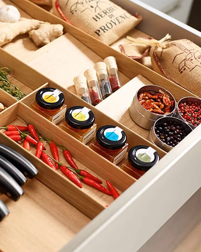 Organized kitchen drawer with Kessebohmer MosaiQ dividers, offered by Mebel Arts, filled with spices and accessories.