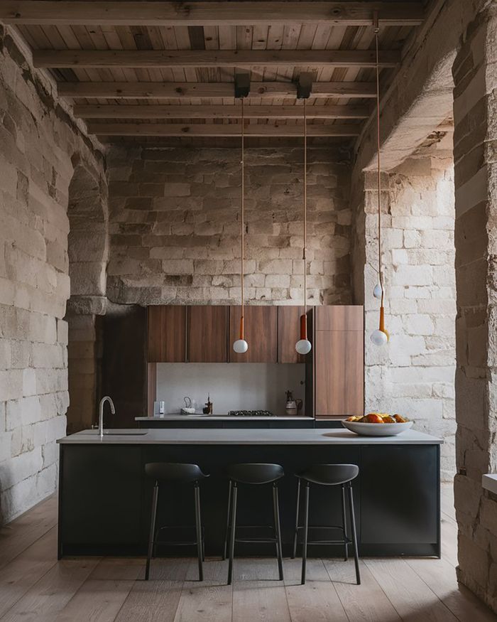 Modern Greek kitchen furniture in a space with stone walls creates a contrast with the historical Greek architecture.