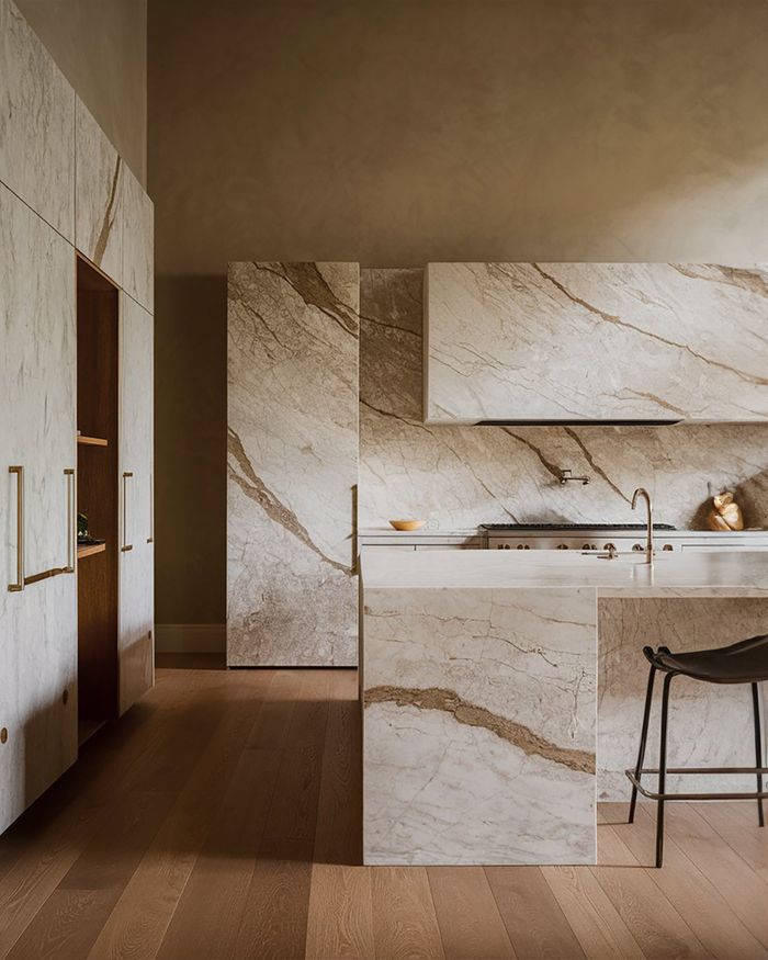 A modern kitchen with wooden furniture and a marble countertop. The combination of natural materials brings elegance and luxury to the space.