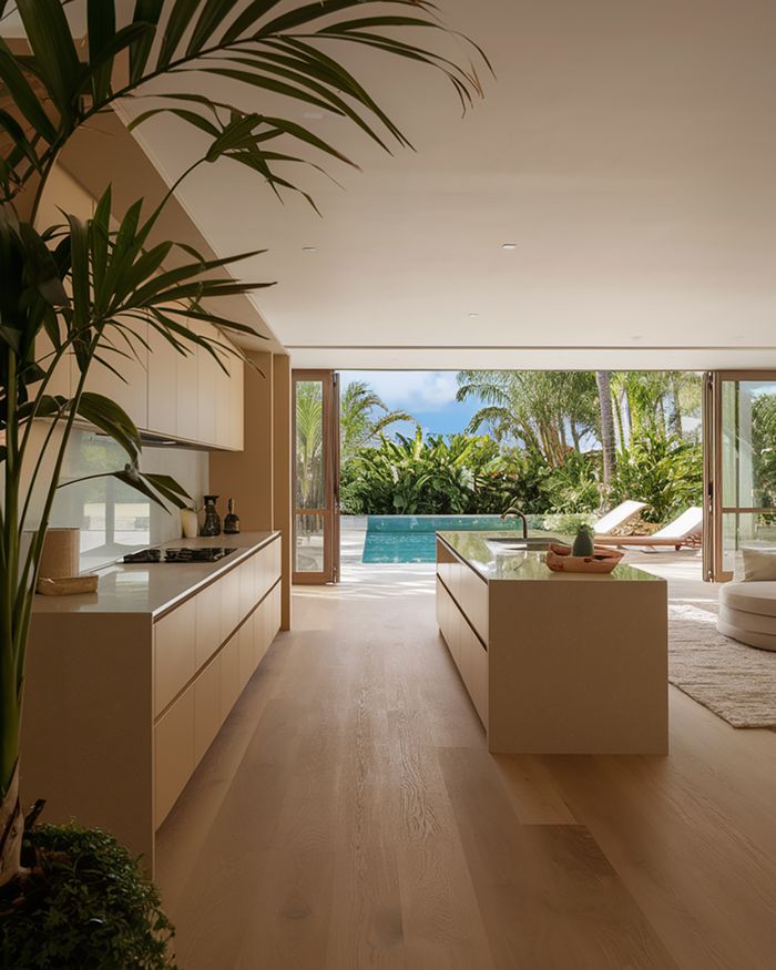 Modern kitchen by Mebel Arts in a light shade with wooden flooring and plants. Large windows overlook a garden with a pool and loungers.