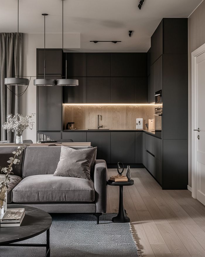 Kitchen with island in dark shades, lighting, and a gray sofa. Mebel Arts