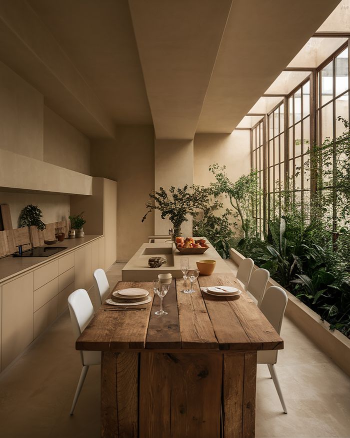 Kitchen furniture with a wooden table and an island next to windows with plants. Mebel Arts.