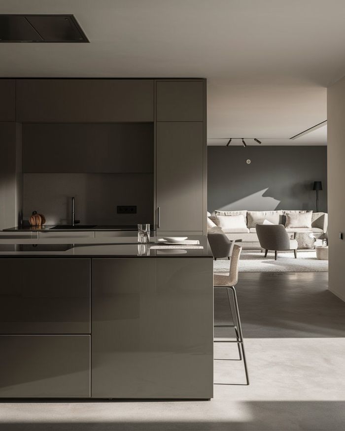 Modern kitchen with gray cabinets and an island. In the background, a living room with comfortable sofas and armchairs is visible. Ideal kitchen furniture.